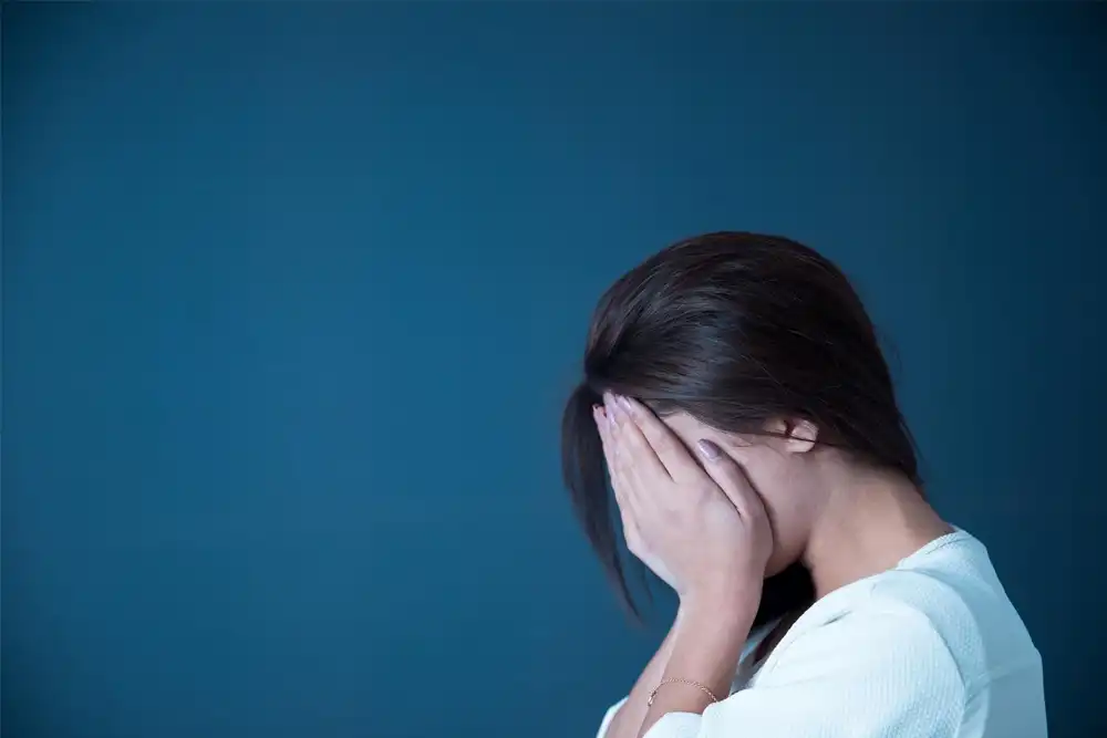 Mujer llevándose las manos a la cara sufriendo uno de los síntomas de la ansiedad más comunes